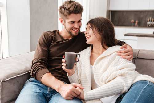 Couple drinking tea together on the sofa.